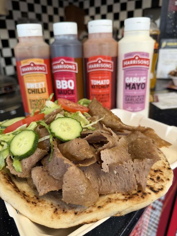 German doner on toasted naan bread with salad and a row of sauces behind it