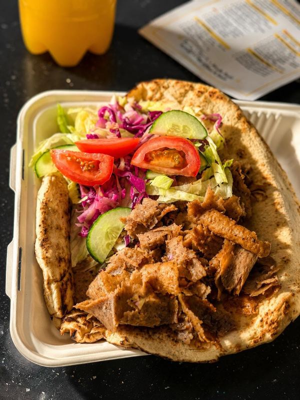 Mixed doner and chicken kebab on naan with salad, red cabbage and tomato in a takeaway box